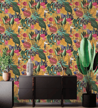Load image into Gallery viewer, Wallpaper of a fantastical jungle scene with a monocle-wearing bush baby and a parrot with a crown. Also features exotic leaves, mushrooms, fruit, and flowers, with toucan and lizard characters. Multi-colored with a rich ochre yellow background.
